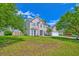 Charming two-story home with well-manicured front yard and mature trees on a bright sunny day at 9682 Pebble Creek Blvd, Summerville, SC 29485