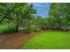 A view of the front yard featuring mulch, green grass, and plenty of trees at 1304 Elm Hall Cir, Summerville, SC 29483