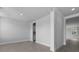 Open-concept living area with gray plank flooring, white walls, and an open hallway at 135 Lilac Grove Way, Summerville, SC 29486