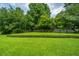 This backyard features a well-manicured lawn, lush trees, and a white picket fence at 1409 Bloomingdale Ln, Mount Pleasant, SC 29466