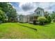 This backyard features a well-manicured lawn, lush trees, and a back porch at 1409 Bloomingdale Ln, Mount Pleasant, SC 29466