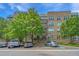 Exterior view of a multi-story condo building with parking, mature trees and blue skies at 145 Pier View St # 214, Daniel Island, SC 29492