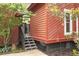 Home exterior featuring a small set of stairs and a feeder with red siding, complemented by landscaping and a grey fence at 152 Mansfield Blvd, Charleston, SC 29418