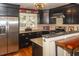 Well-equipped kitchen with stainless steel refrigerator, black cabinets, granite countertops, and tile backsplash at 152 Mansfield Blvd, Charleston, SC 29418