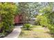 Side yard of red home featuring mature trees, walkway, and privacy fence at 152 Mansfield Blvd, Charleston, SC 29418