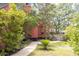Side yard of red home featuring mature trees, walkway, and privacy fence at 152 Mansfield Blvd, Charleston, SC 29418