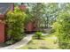 Side yard of red home featuring mature trees, walkway, and privacy fence at 152 Mansfield Blvd, Charleston, SC 29418