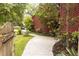 Charming home's walkway leads to the front door through a lush, landscaped yard, with exterior of the home with red siding at 152 Mansfield Blvd, Charleston, SC 29418
