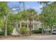 Two-story home featuring double porches, mature trees, and an American flag creating a welcoming facade at 183 Civitas St, Mount Pleasant, SC 29464