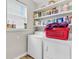 Bright laundry room with floating shelves, white washer and dryer, and natural light from a large window at 193 Cypress Forest Dr, Moncks Corner, SC 29461