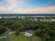 Aerial view of a luxury home surrounded by lush greenery and a river under an early evening sky at 2962 Anchor Watch Dr, Wadmalaw Island, SC 29487