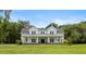 Charming two-story white farmhouse with a covered porch, metal roof, and large green front yard at 2962 Anchor Watch Dr, Wadmalaw Island, SC 29487