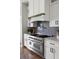 Close-up of a gourmet kitchen featuring a stainless steel range, custom hood, and elegant herringbone backsplash at 2962 Anchor Watch Dr, Wadmalaw Island, SC 29487
