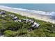 Gorgeous aerial of condos nestled between verdant trees and a picturesque sandy beach and tranquil ocean at 4303 Sea Forest Dr, Kiawah Island, SC 29455