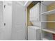 Convenient laundry closet features a stacked washer and dryer, plus storage shelves for laundry essentials at 4303 Sea Forest Dr, Kiawah Island, SC 29455