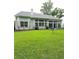 Back exterior showcasing a sunroom surrounded by a well-kept yard and mature trees at 605 Pointe Of Oaks Rd, Summerville, SC 29485