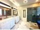 Well-lit bathroom featuring dual vanities, a glass-enclosed shower with herringbone tiling, and marble flooring at 6212 Fieldstone Cir, Charleston, SC 29414