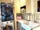 Laundry room features white shaker cabinets, marble backsplash, farmhouse sink, and stacked washer and dryer at 6212 Fieldstone Cir, Charleston, SC 29414