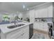 Open kitchen featuring white cabinets, stainless appliances, island with seating, and living area at 7413 Indigo Palms Way, Johns Island, SC 29455