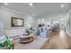 Bright living room with hardwood floors, white sofa and chairs, and open floor plan to kitchen at 7413 Indigo Palms Way, Johns Island, SC 29455