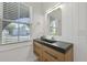 Bathroom vanity with a black countertop, modern faucet, wood drawers, an ornate mirror and natural light at 868 Tripe St, Charleston, SC 29407