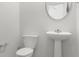 Neutral bathroom with a pedestal sink, toilet, round mirror, and neutral paint at 107 Moscato Ln, Summerville, SC 29485