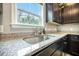 Close-up of a kitchen sink with granite countertops, dark wood cabinets, and a window providing natural light at 141 Pine Crest View Dr, Summerville, SC 29486