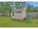 Tan shed with double doors and a window sits in a grassy backyard, surrounded by a wooden fence at 184 Kirkland St, Goose Creek, SC 29445