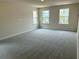 Spacious bedroom featuring soft gray carpet and three windows offering natural light and neighborhood views at 2018 Quiet Ibis Rd, Hanahan, SC 29410