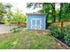 Charming blue storage shed in the backyard, surrounded by lush greenery at 209 Apache Dr, Summerville, SC 29483