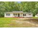 Charming single-story home featuring a covered front porch, black shutters, and mature trees at 2202 Sc-61, Ridgeville, SC 29472