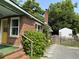 Brick home exterior featuring a chimney, wooden fence, lush greenery and a quaint storage shed in the backyard at 2204 Dover St, North Charleston, SC 29405