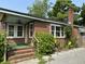 Charming brick home with a cozy front porch, complemented by lush landscaping and vibrant greenery at 2204 Dover St, North Charleston, SC 29405