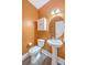 This vibrant half-bathroom features a pedestal sink, storage cabinet, and charming orange walls at 2336 Brinkley Rd, Johns Island, SC 29455