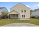 A yellow two-story home with a screened porch, small patio, and a well-maintained lawn in the backyard at 251 Emerald Isle Dr, Moncks Corner, SC 29461