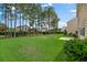 View of a large, grassy backyard featuring mature trees and a partial view of neighboring homes at 272 Overcup Loop, Summerville, SC 29486