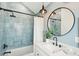 Stylish bathroom features blue tile, modern vanity, round mirror and pendant lighting at 313 E Arctic Ave, Folly Beach, SC 29439