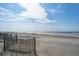 Wide sandy beach with natural fencing, calm ocean waters, and scattered beach visitors at 313 E Arctic Ave, Folly Beach, SC 29439