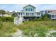Charming beach house with an elevated porch, a car port, and lush landscaping at 313 E Arctic Ave, Folly Beach, SC 29439