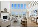 Bright living room featuring a fireplace, hardwood floors, and wall of windows with ocean views at 313 E Arctic Ave, Folly Beach, SC 29439
