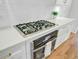 Close-up of a cooktop and oven with white cabinets, gold hardware, and quartz countertops at 400 Bay Crossing Rd, Mount Pleasant, SC 29464