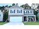 Two-story home featuring a two-car garage, gray brick accents, black shutters, and well-maintained landscaping at 619 Red Mulberry Rd, Moncks Corner, SC 29461
