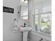 Charming bathroom featuring a pedestal sink, decorative mirror, and window at 626 Chigwell Springs Ln, Summerville, SC 29486