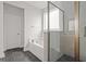 Bright bathroom with a glass enclosed shower, soaking tub, and gray tile at 772 Opal Wing St, Moncks Corner, SC 29461