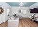 Bright living room with a gray sectional couch, wood floors, a blue ceiling, and white walls at 8562 N Highway 17, McClellanville, SC 29458