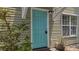 Charming teal front door with a small porch surrounded by green shrubs and plants at 8743 Grassy Oak Trl, North Charleston, SC 29420