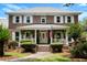 Beautiful two-story brick home with a welcoming front porch, American flag, and manicured lawn at 910 Kushiwah Creek Ct, Charleston, SC 29412