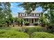 Charming brick home featuring a welcoming front porch, lush landscaping, and a well-manicured lawn at 910 Kushiwah Creek Ct, Charleston, SC 29412