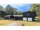 Landscaped home exterior features a chic dark facade, two-car garage, and lush lawn at 1211 Lem Rd, Cordesville, SC 29434
