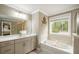 Bright bathroom featuring a soaking tub with a window view, neutral colors, and a large mirror above the vanity at 125 Beam St, Huger, SC 29450